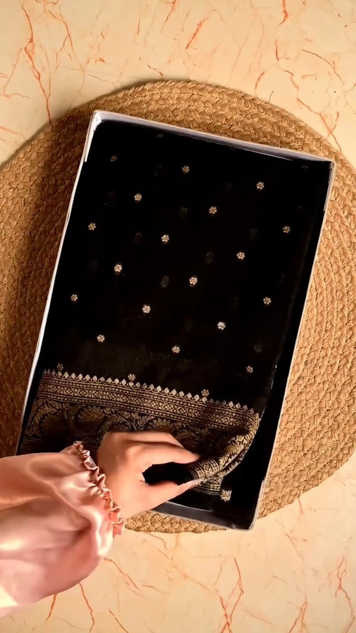 Black embroidered fabric in a box on a textured surface